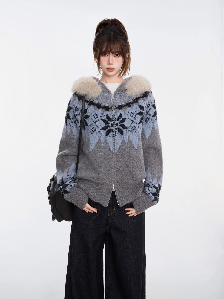 Woman in a grey and blue Fair Isle knit zip-up cardigan with a faux fur trim hood, hands in pockets, and black wide-leg jeans