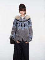 Woman in a grey and blue Fair Isle knit zip-up cardigan with a faux fur trim hood, hands in pockets, and black wide-leg jeans