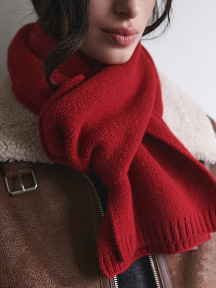 Close-up of a red knitted scarf worn around a woman's neck.