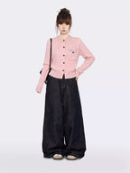 Woman standing with a pink cable knit cardigan and dark wide-leg jeans, showcasing the outfit from the front.