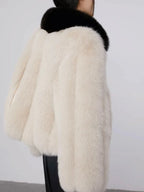 Back view of a cream faux fur cropped jacket with a black collar.