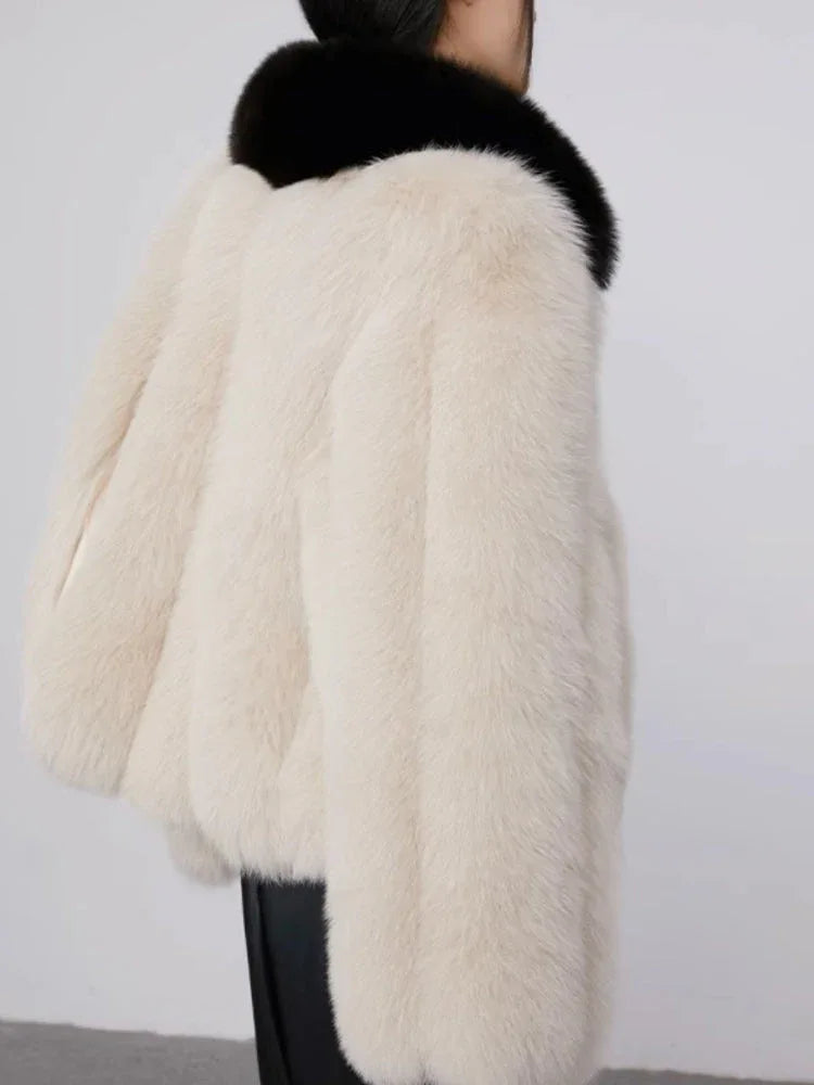 Back view of a cream faux fur cropped jacket with a black collar.