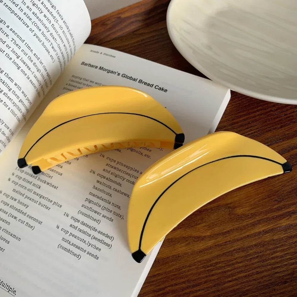 Two yellow banana-shaped hair clips placed on an open cookbook, showcasing a recipe.