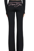 Back view of the black flared pants with embroidered text 'I Am Gia'.