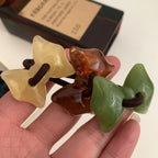Hand holding yellow, amber, and green bow-shaped hair ties