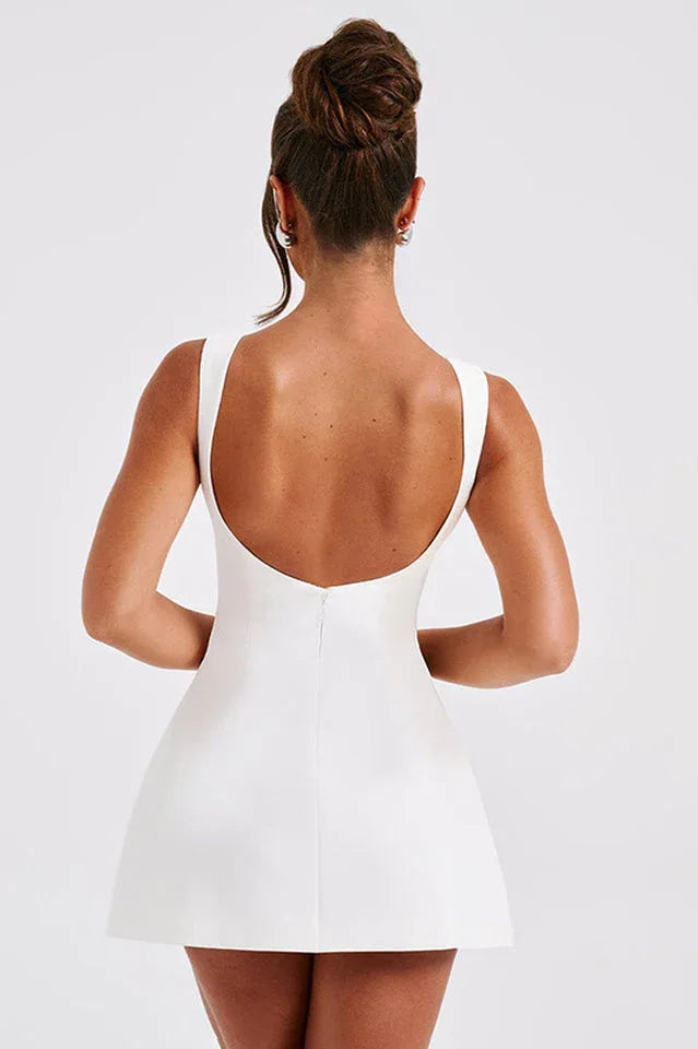 Back view of a woman wearing a white sleeveless boat neck mini dress showing a low scoop back.
