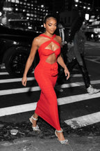 woman walking in a red halter neck maxi dress with cutout and rose detail at night