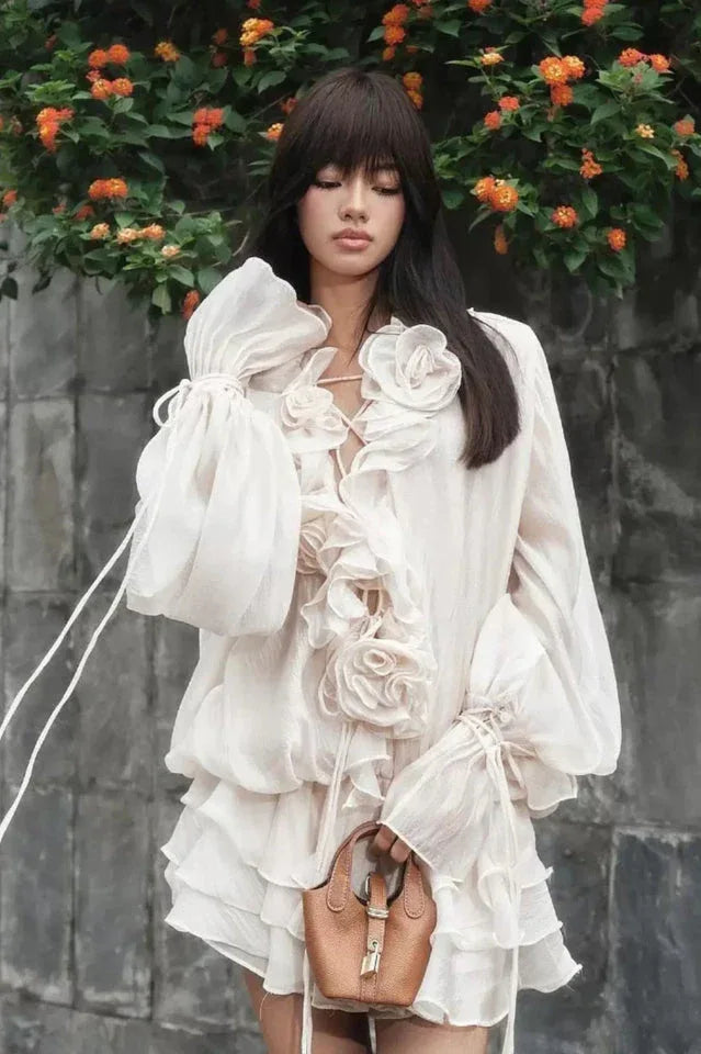 close-up of a woman in a white ruffled dress with floral details and a small handbag
