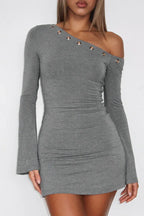 Woman wearing a grey one-shoulder long-sleeve bodycon dress with flared sleeves and decorative grommets.