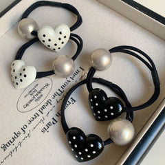 Close-up of heart-shaped hair ties with polka dots and silver beads in a tray