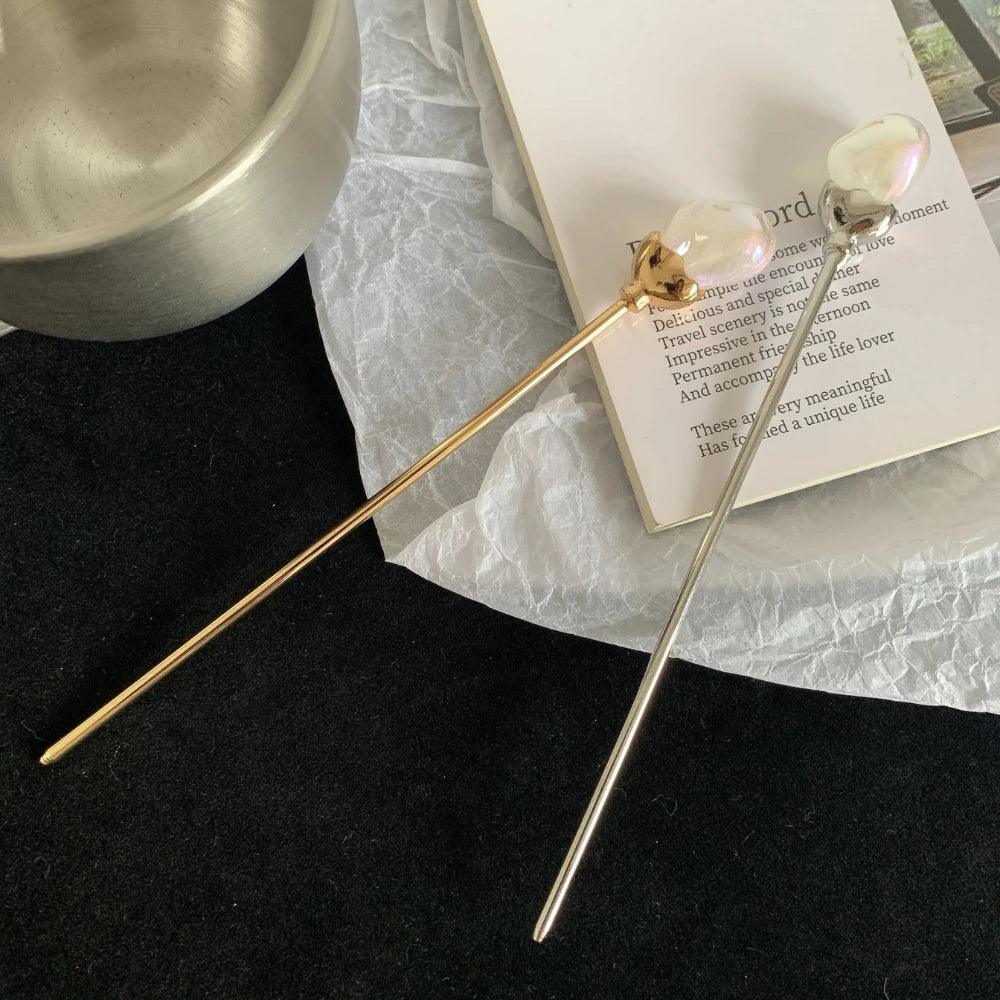 Two hairpins, gold and silver, are placed on a book with text.