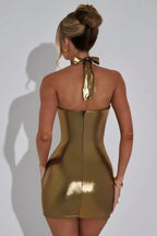 Woman wearing a gold metallic halter dress with a draped cowl neckline, side profile.