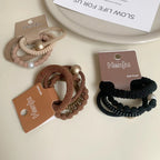 A collection of three sets of coiled hair ties, each with different color combinations and decorative elements like pearls and beads.