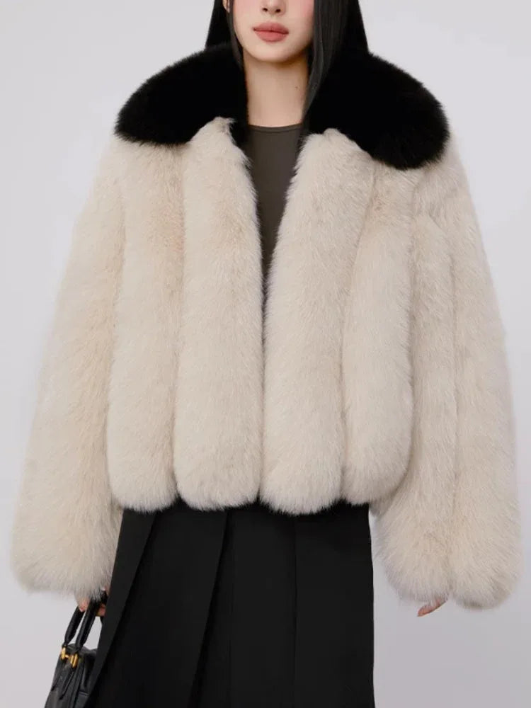 Woman wearing a cream faux fur cropped jacket with a black collar and a black dress, holding a black handbag.