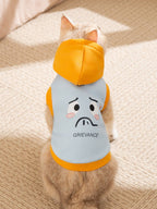 The back of a cat wearing a light blue hoodie with a sad face graphic print and orange trim.