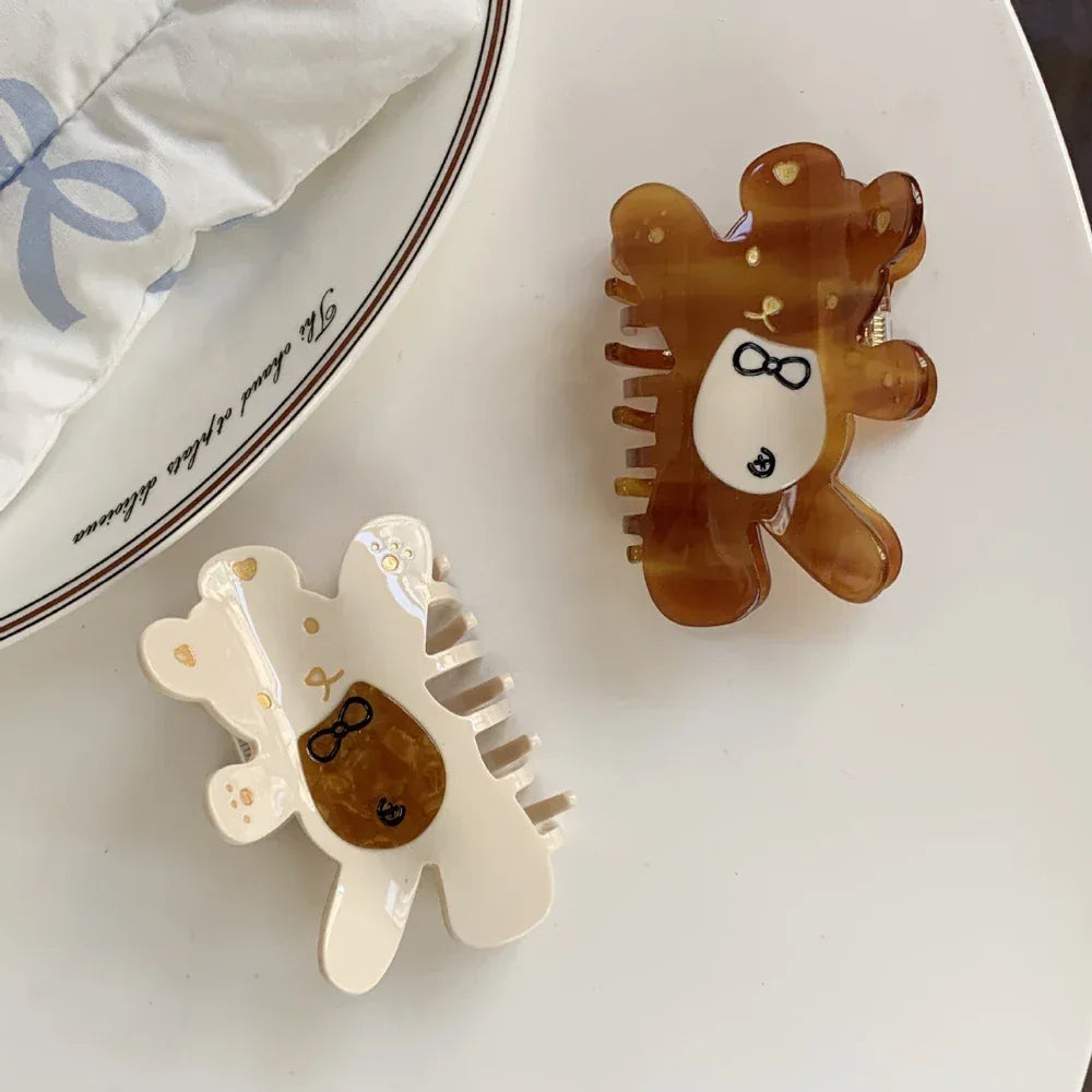 two bear claw hair clips, one brown and one cream, arranged on a white surface