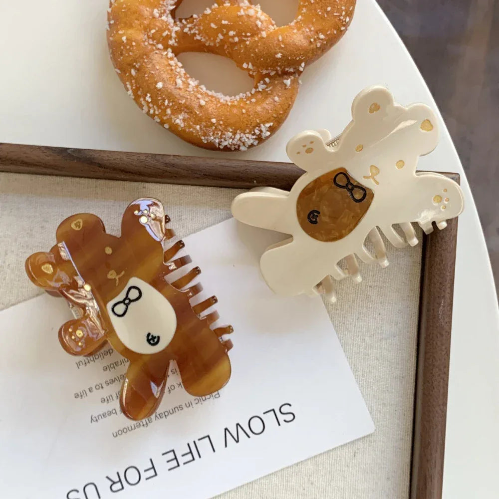 two bear claw hair clips, one brown and one cream, with pretzels in the background