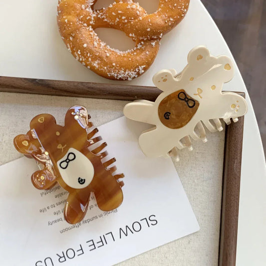 two bear claw hair clips, one brown and one cream, with pretzels in the background
