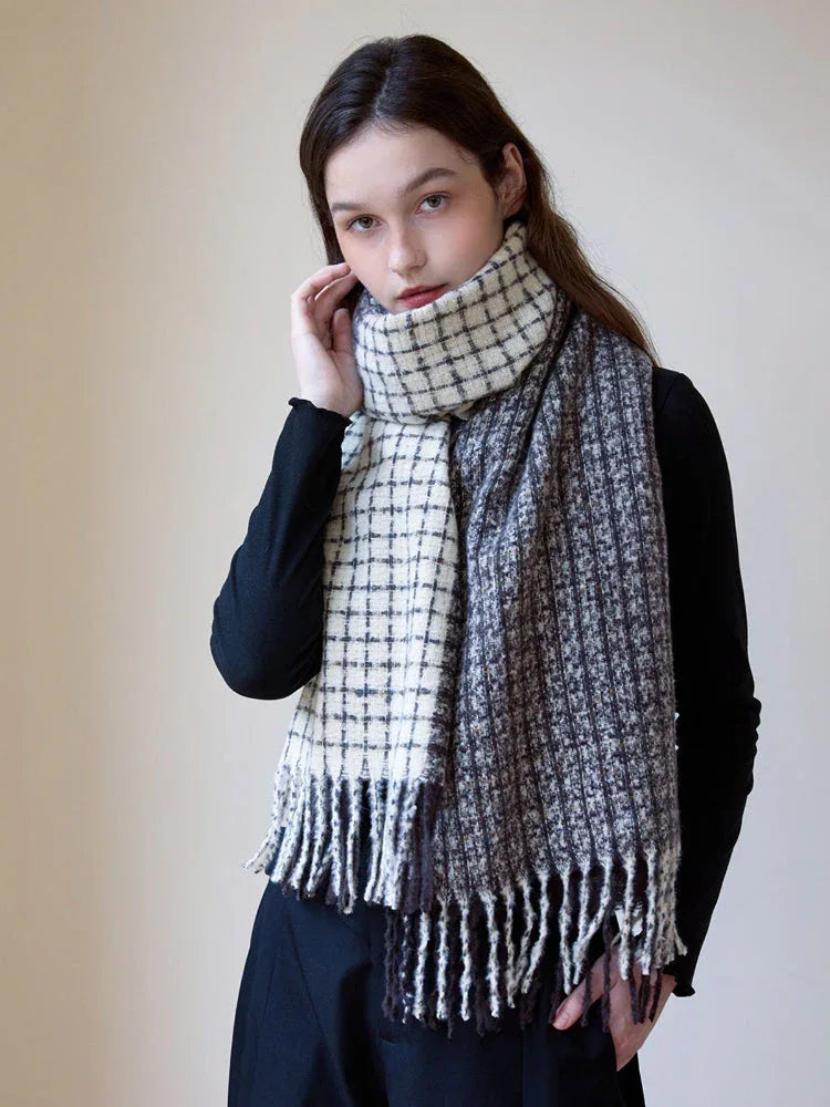 Woman wearing a black long-sleeve top and a plaid scarf with fringe detail, styled loosely around her neck.