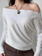 Front view of a white off-the-shoulder knit top with a butterfly pendant necklace.