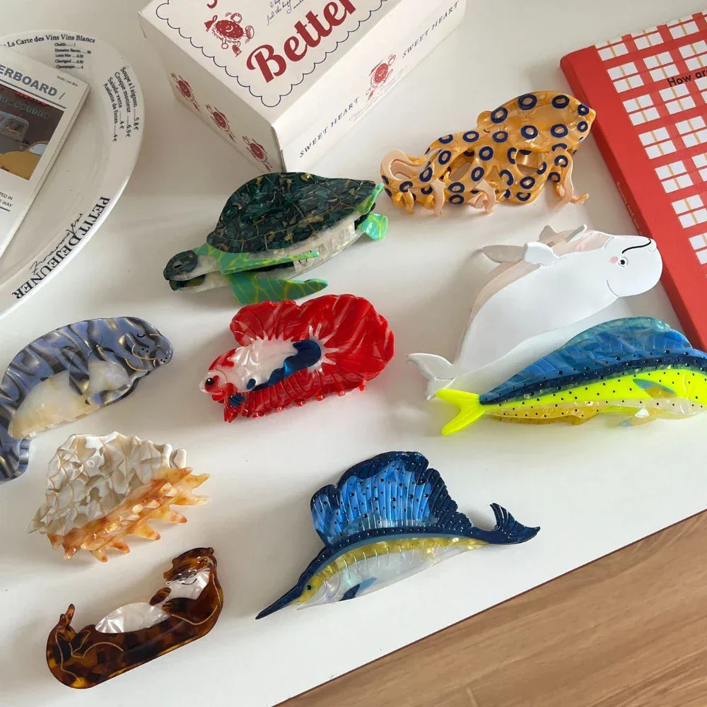 Collection of decorative hair clips including a sailfish, dolphin, turtle, octopus, otter, fish, whale, and seashell