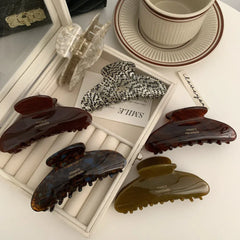 A selection of tortoiseshell patterned hair claw clips displayed in a white jewelry organizer tray, with a handwritten 'SMILE' tag.