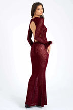 Woman wearing a long-sleeved, burgundy, animal print, sheer mesh dress with feathered cuffs and an open back, back three-quarter view.
