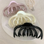 close-up of three octopus claw hair clips in black, pink, and cream