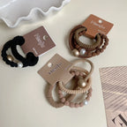 Overhead view of three sets of coiled hair ties in black, brown, and beige, featuring pearl and metallic bead details.