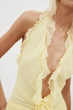 Detail of the neckline of a yellow ruffled halter mini dress