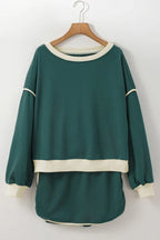 Green crew neck sweatshirt with cream trim hanging on a wooden hanger