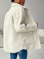 Back view of a woman wearing an oversized white sherpa fleece jacket, showing the pockets.