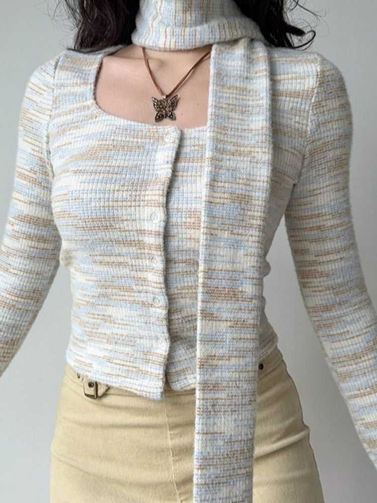 Front view of a woman wearing a light blue, white, and tan striped knit cardigan with a square neckline and an attached scarf.