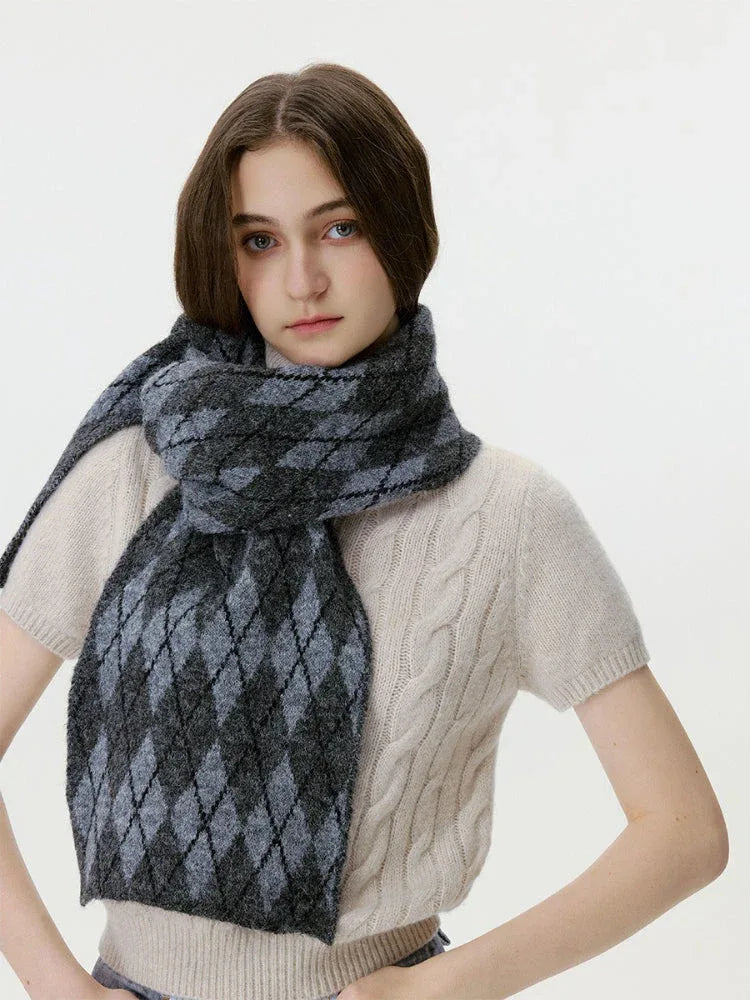 Woman adjusting her cream cable-knit sweater and a grey and black argyle scarf