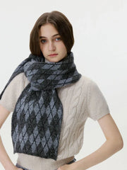 Woman adjusting her cream cable-knit sweater and a grey and black argyle scarf