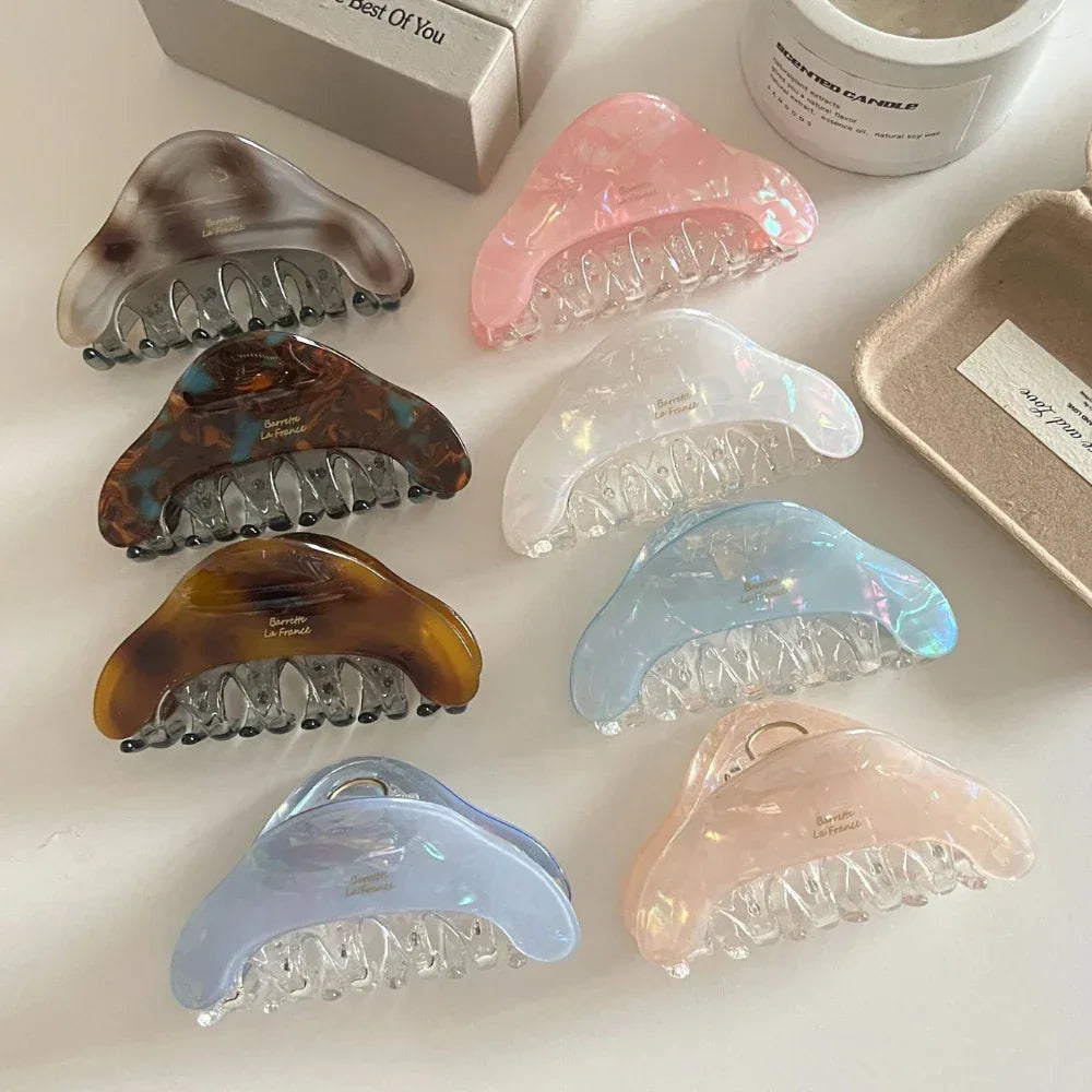 Several iridescent hair claws in different colors, including pink, blue, and white.