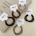 A variety of JQian elastic hair ties in neutral shades, displayed on top of a book.