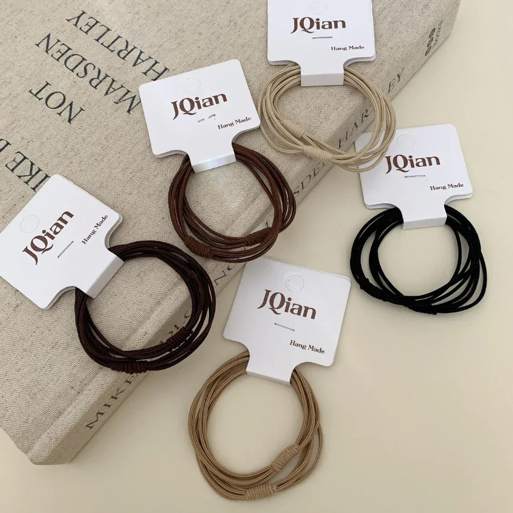 A variety of JQian elastic hair ties in neutral shades, displayed on top of a book.