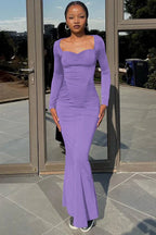 woman wearing a long purple ruched dress with a flare hem from the side