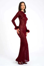 Woman wearing a long-sleeved, burgundy, animal print, sheer mesh dress with feathered cuffs and a mermaid hem, side view.
