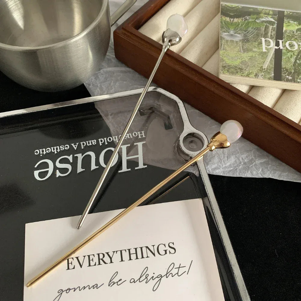 A gold-tone and silver-tone hairpin are arranged on various decorative items and text.
