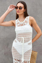 Woman's face and upper body wearing a white crochet knit maxi dress and sunglasses.