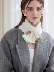 Woman in a grey coat with a white and tan striped scarf tied around her neck