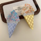 Two ice cream cone hair clips, one blue and one yellow, on a wooden tray.