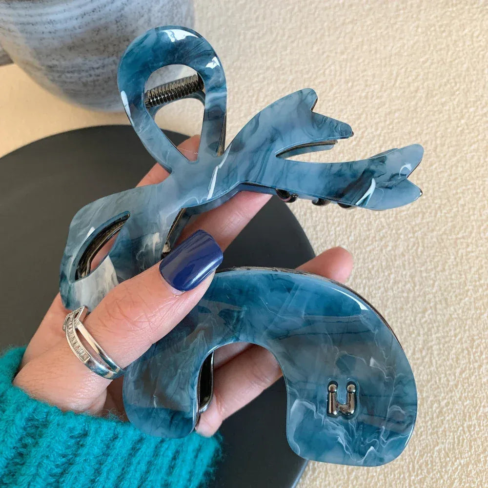 hand holding a blue marbled bow hair claw