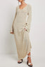 woman wearing a cream textured knit maxi dress with long bell sleeves and a v-neckline, paired with platform sandals