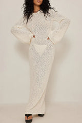 woman wearing a white textured knit maxi dress with long bell sleeves and a round neckline, paired with platform sandals