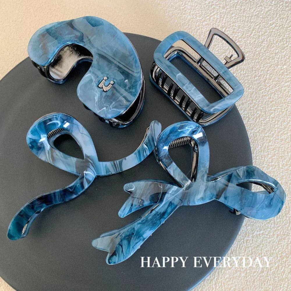 three blue marbled hair claws on a dark plate