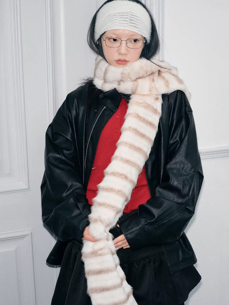 Model wearing a cream and brown striped faux fur scarf, black jacket, and red top.