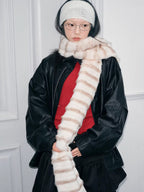Model wearing a cream and brown striped faux fur scarf, black jacket, and red top.